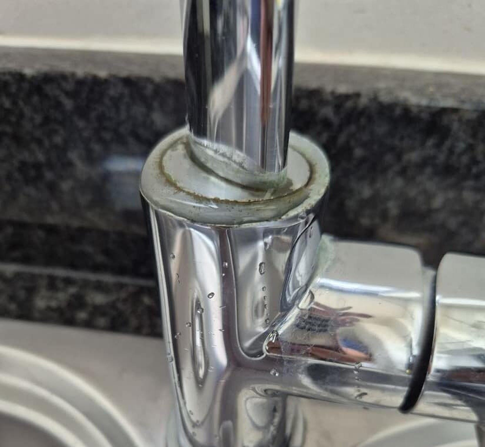 Real ERS close-up of a leaking kitchen mixer with visible water droplets